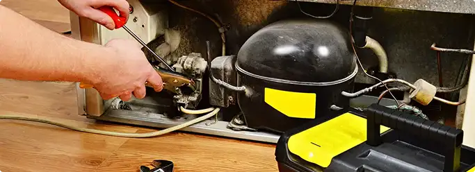 Refrigerator repair technician fixing the compressor and wiring in Vandalia, OH