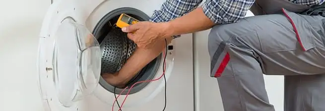 Dryer repair technician inspecting and repairing a clothes dryer in Dayton, OH