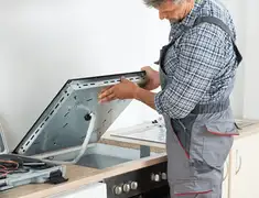 Appliance repair technician installing a built-in cooktop in Dayton, OH
