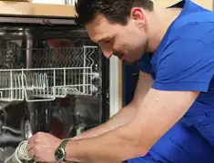 Dishwasher repair technician inspecting and servicing an open dishwasher in Dayton, OH