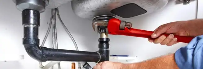 Garbage disposal repair technician tightening the sink drain and disposal connection in Dayton, OH