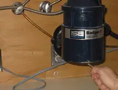 Garbage disposal repair technician tightening the mounting ring under a sink in Dayton, OH