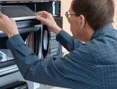 Appliance repair technician replacing a microwave vent filter in Dayton, OH