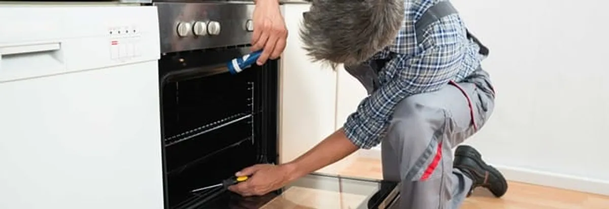 Oven repair technician inspecting and servicing an electric oven in Dayton, OH