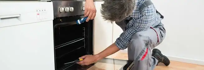 Oven repair technician inspecting and servicing an electric oven in Dayton, OH