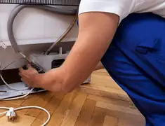 Appliance repair technician fixing refrigerator water line and connections in Dayton, OH