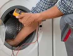 Washing machine repair technician testing a front-load washer with diagnostic tools in Dayton, OH