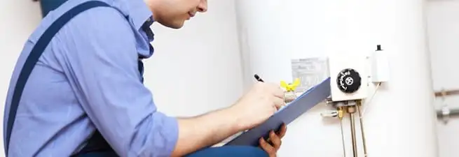 Water heater repair technician inspecting the unit and recording service notes in Dayton, OH