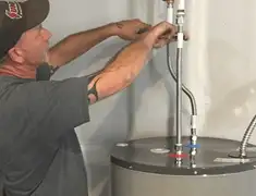 Water heater repair technician tightening supply line connections in Dayton, OH