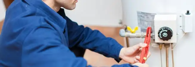Water heater repair technician adjusting the temperature control and gas valve in Dayton, OH